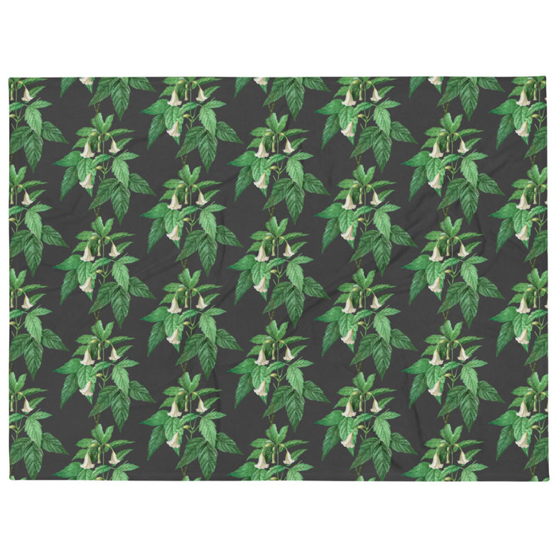 Dark gray throw blanket with repeating botanical pattern of green leaves and white bell flowers