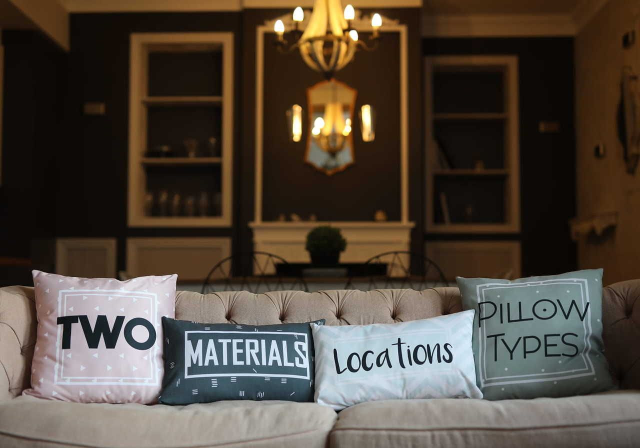 Four decorative pillows on a beige couch, featuring the words "TWO", "MATERIALS", "Locations", and "PILLOW TYPES”.