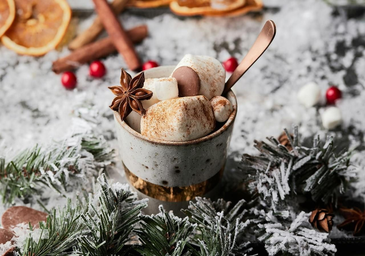 A steaming cup of hot chocolate topped with fluffy marshmallows and a sprinkle of cinnamon.