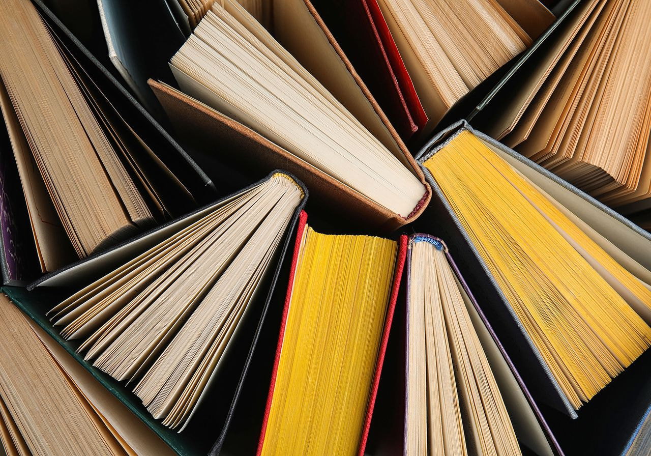 A large pile of books featuring a variety of colorful pages stacked together.