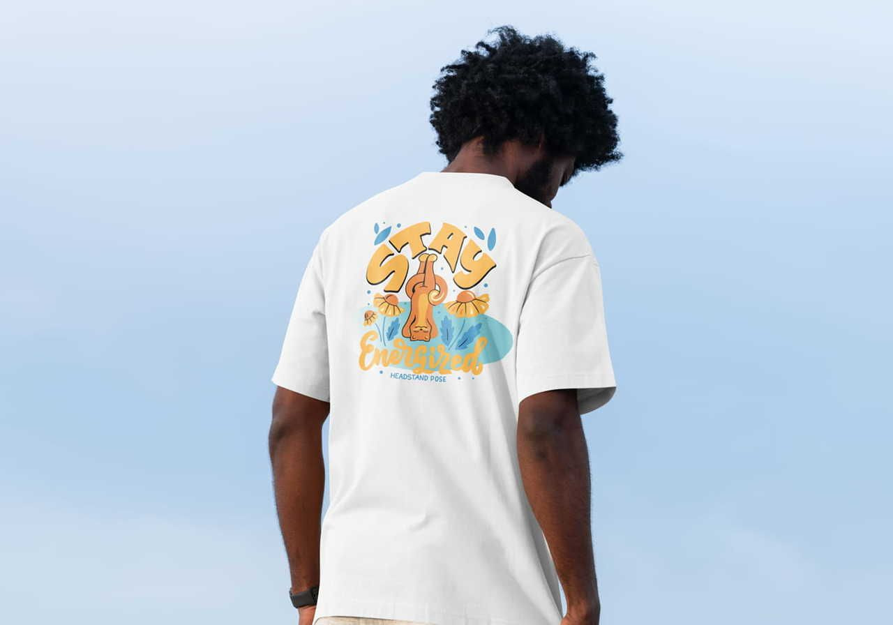 A man with curly hair stands outside, wearing a white t-shirt with colorful illustrations. The shirt displays the text "Stay Energized".