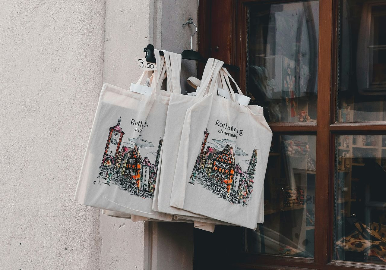 Printed tote bags on a hanger.