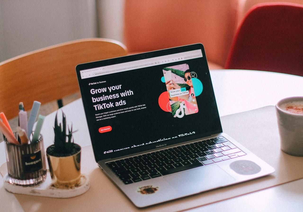 A laptop on a round table displays a website promoting TikTok ads.