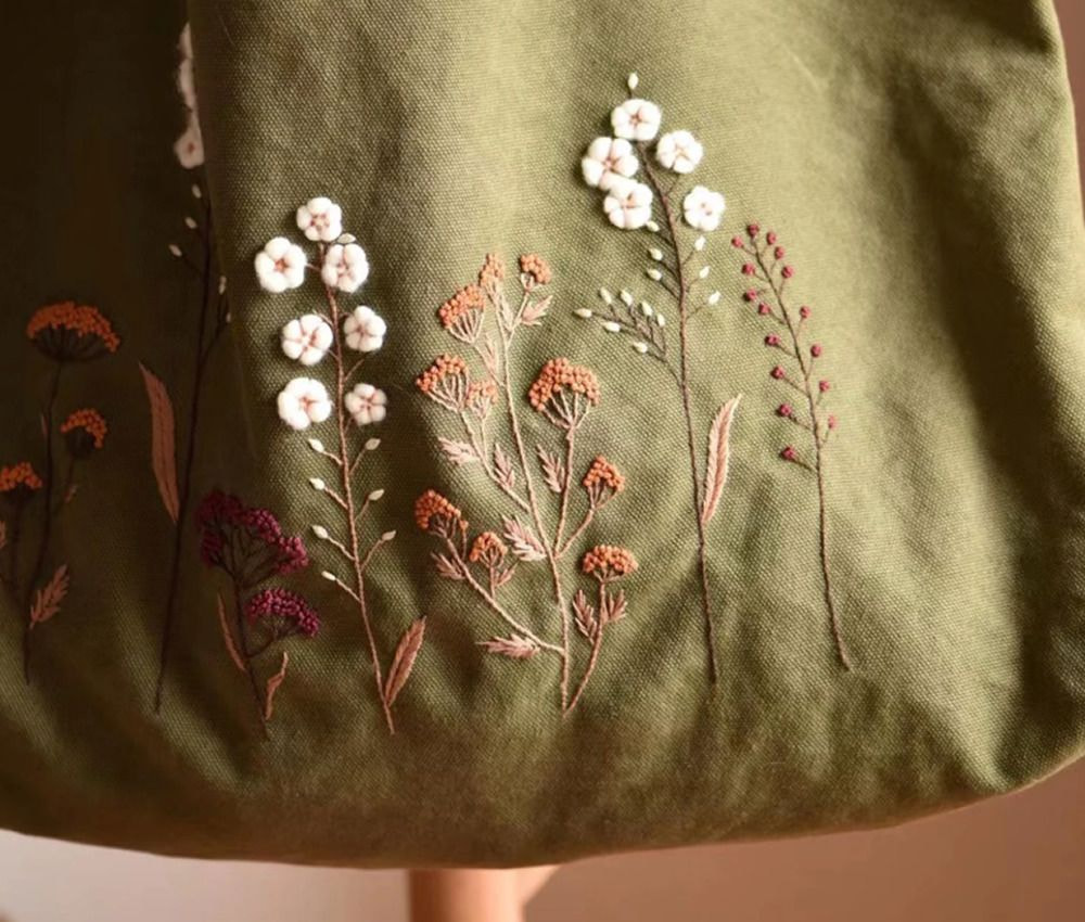 A green bag adorned with colorful flowers and leaves, showcasing a vibrant floral design.