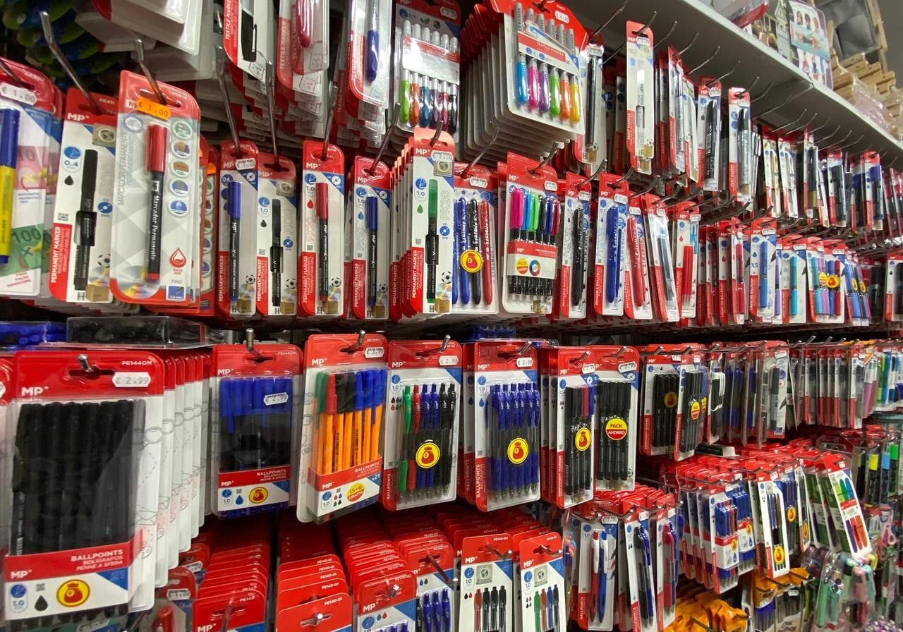 A store display featuring a variety of colorful pens and pencils arranged neatly on shelves.