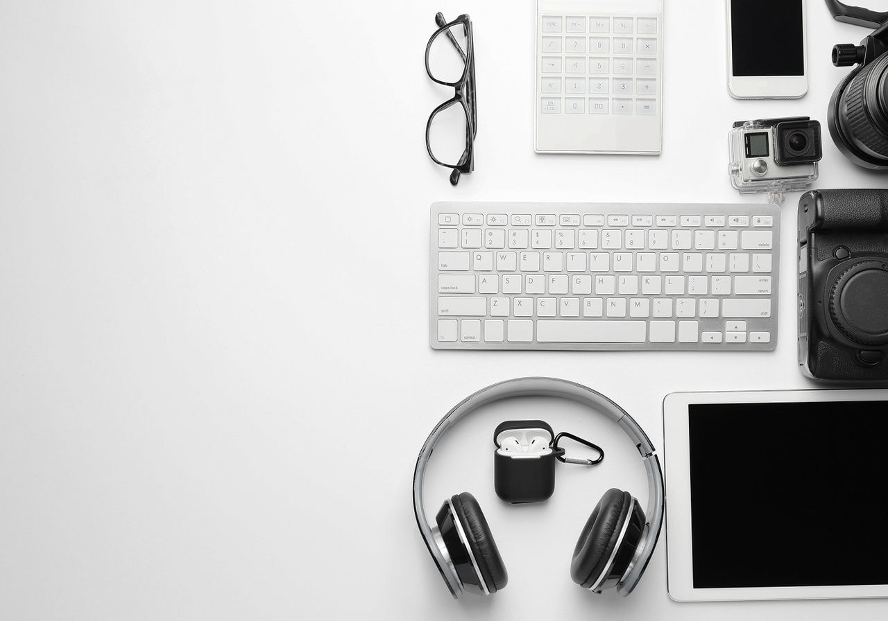 A white desk featuring a laptop, camera, headphones, and various office supplies arranged neatly.