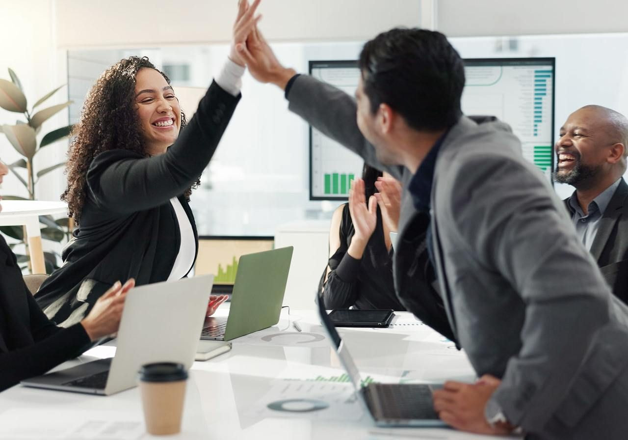 Business colleagues celebrate success with a high five in a modern office setting.