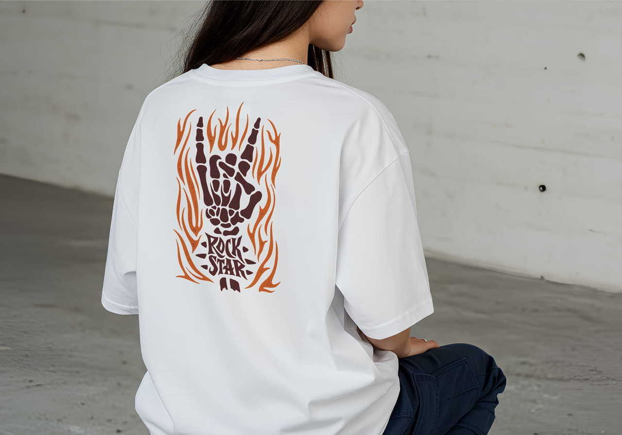 A woman sits wearing a white t-shirt with a graphic of a flaming skeleton hand making a rock gesture. Text below reads "Rock Star”.