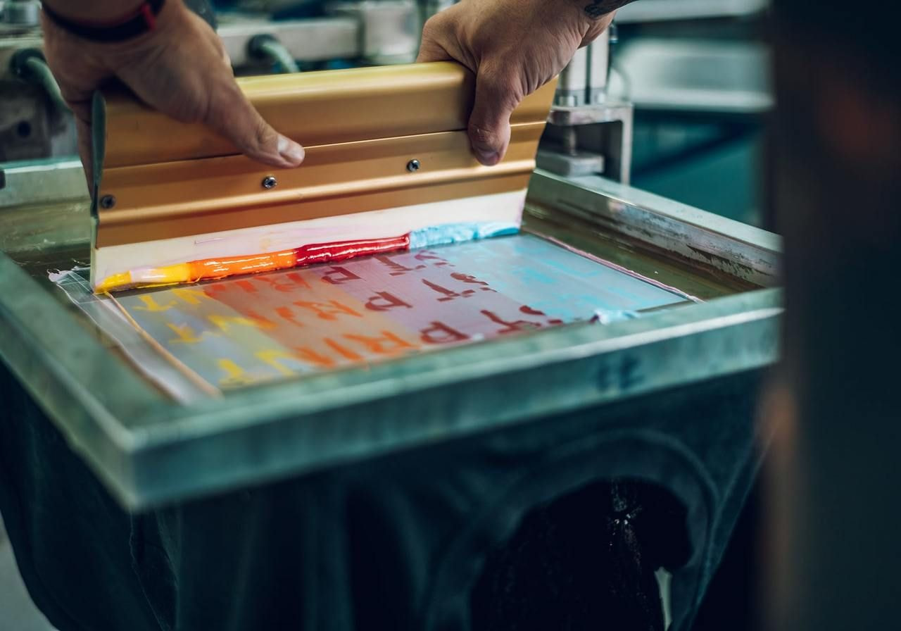 A person is screen printing on a black t-shirt.