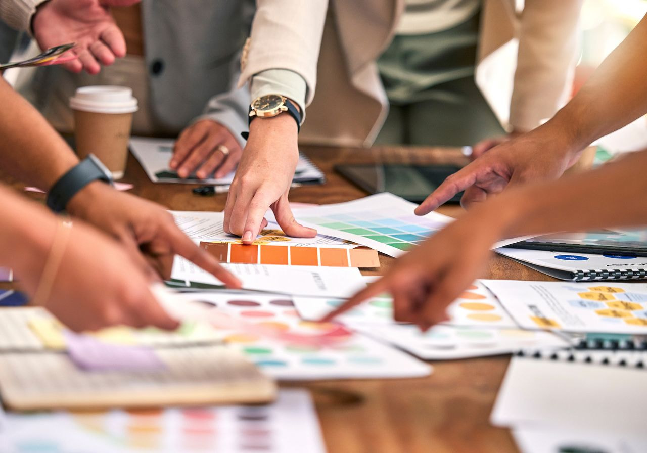 Business professionals collaborating on a project, surrounded by various color samples and design materials.