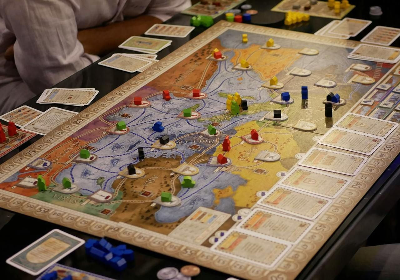 A group of people engaged in a board game, focused on the game pieces and the board layout.