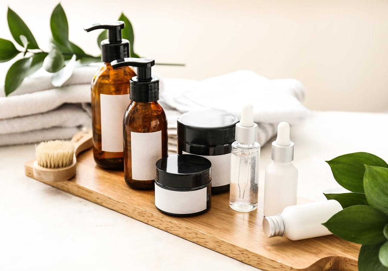 A wooden tray displaying an assortment of cosmetic products, including bottles, jars, and applicators.