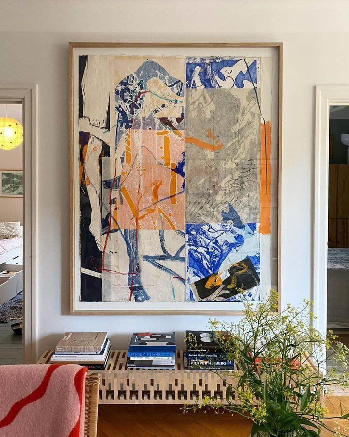 A large painting is displayed above a couch in a cozy living room setting.