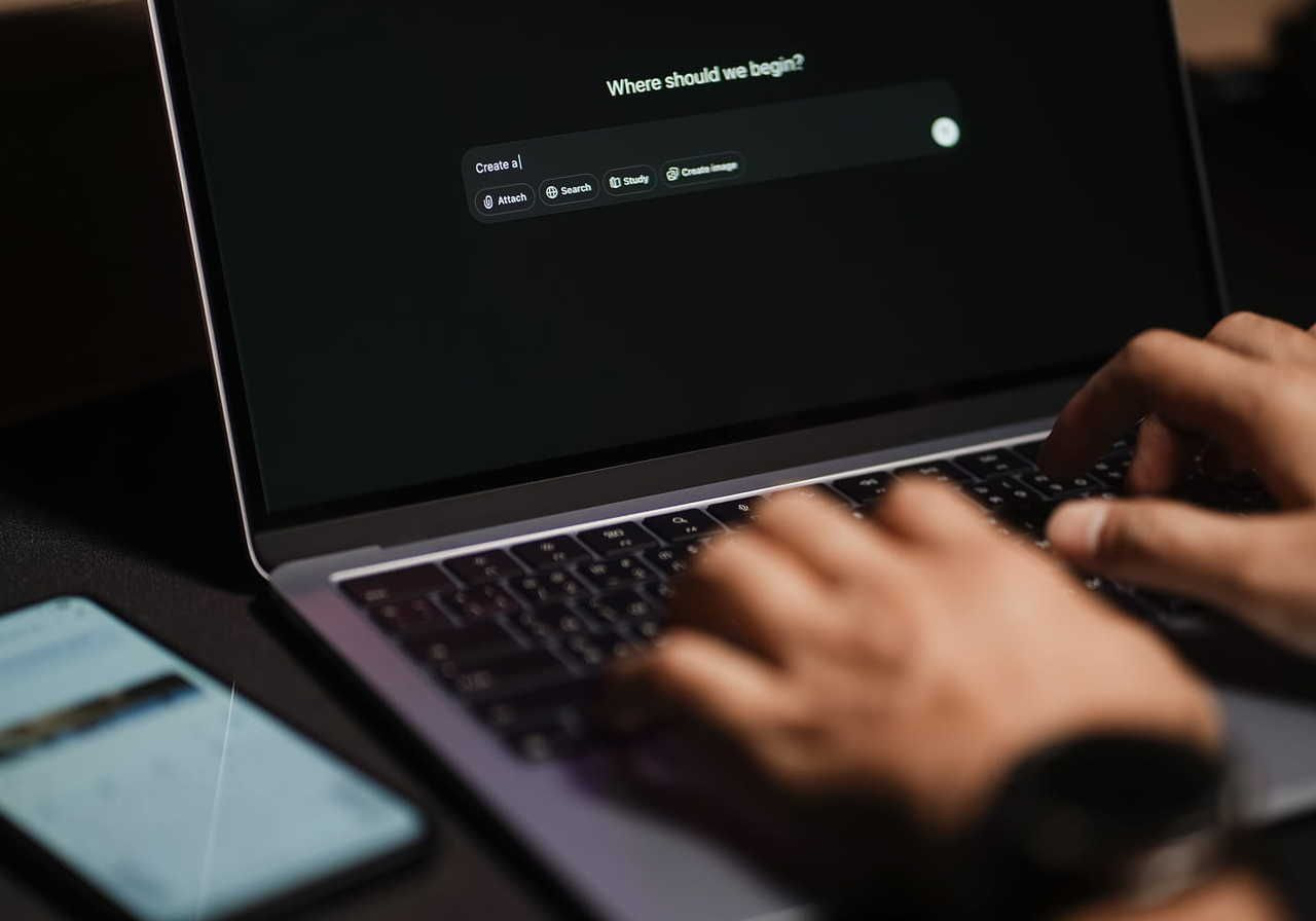 A person typing on a laptop keyboard with a dark screen displaying a prompt that says