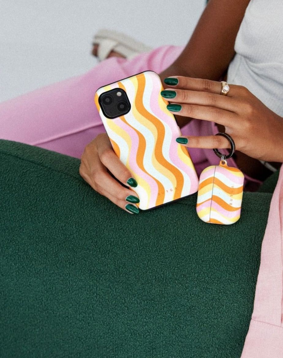 woman holding a matching phone case and headphones case