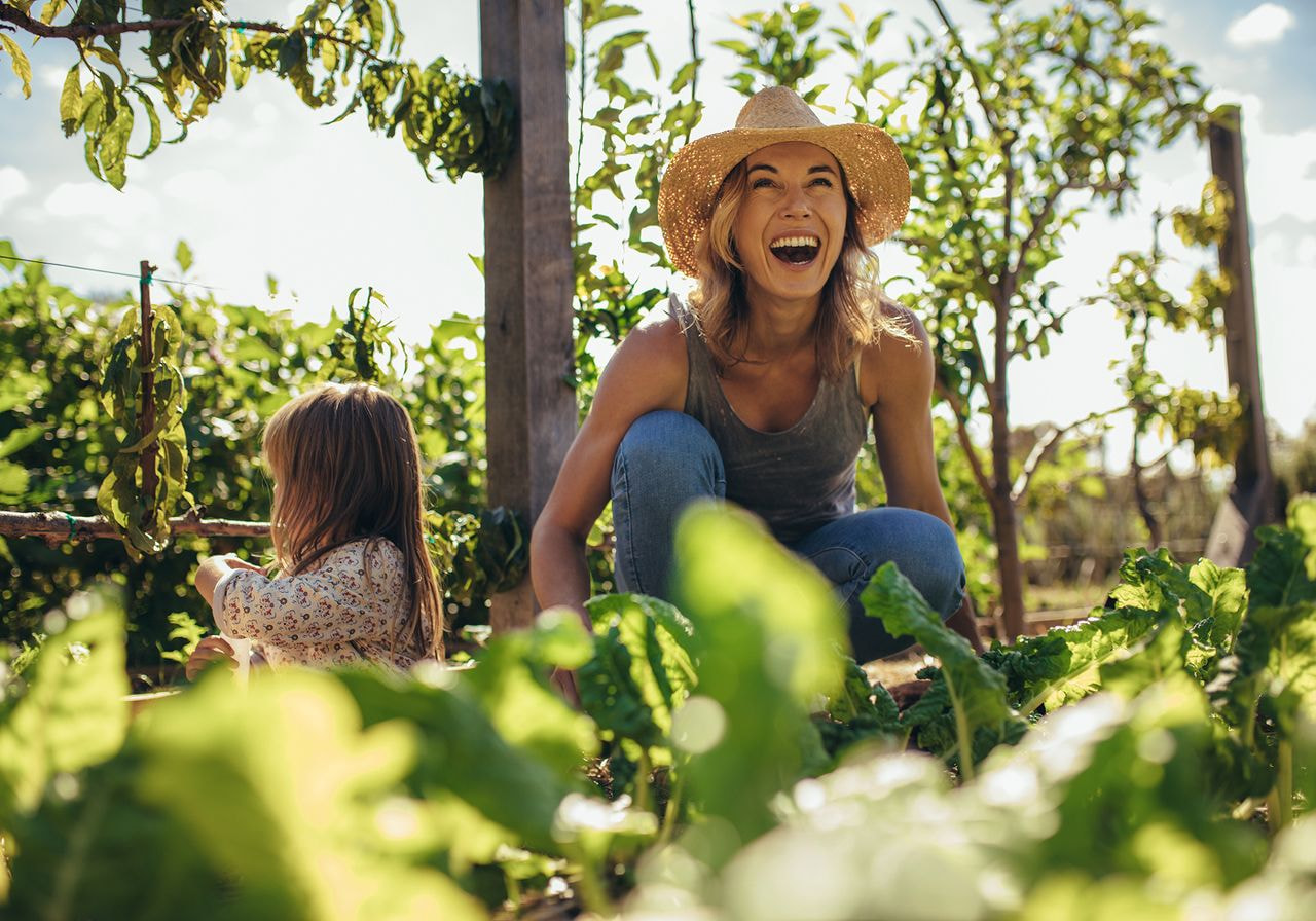 A woman and a child enjoying time together in a vibrant garden filled with flowers and greenery.