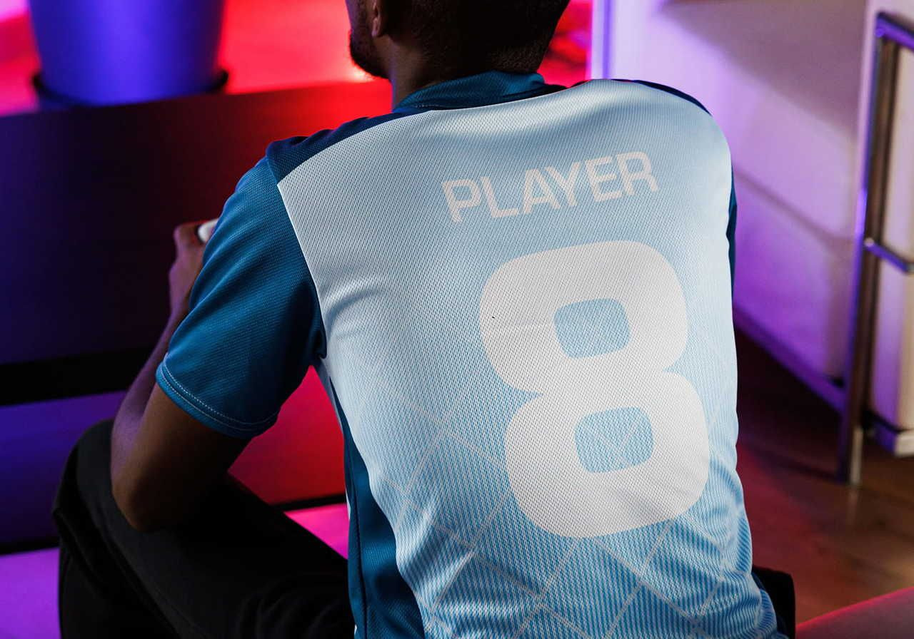 A person sitting with their back towards the camera, wearing a blue sports jersey that has the word