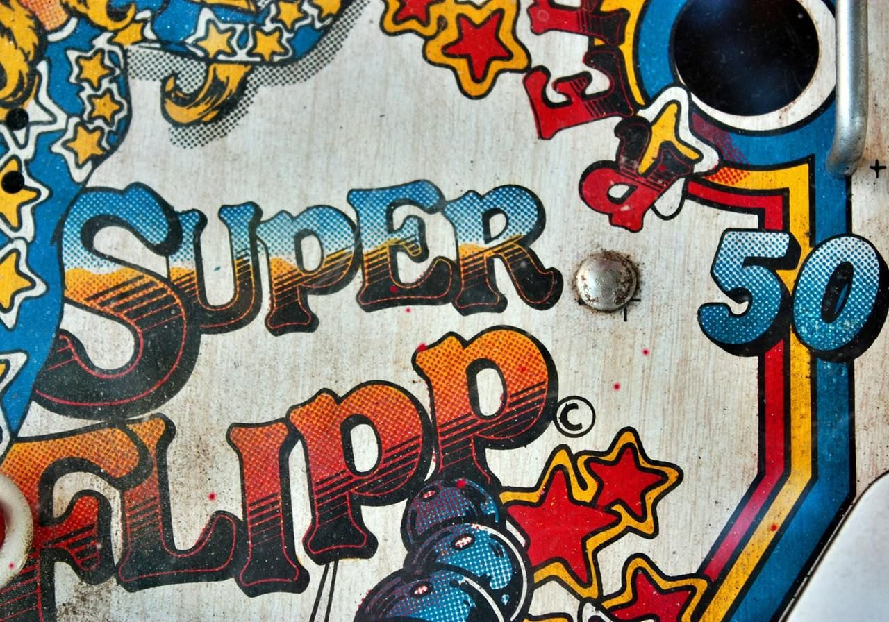 Colorful pinball machine titled "Super Flipper 50" featuring vibrant graphics and classic gameplay elements.