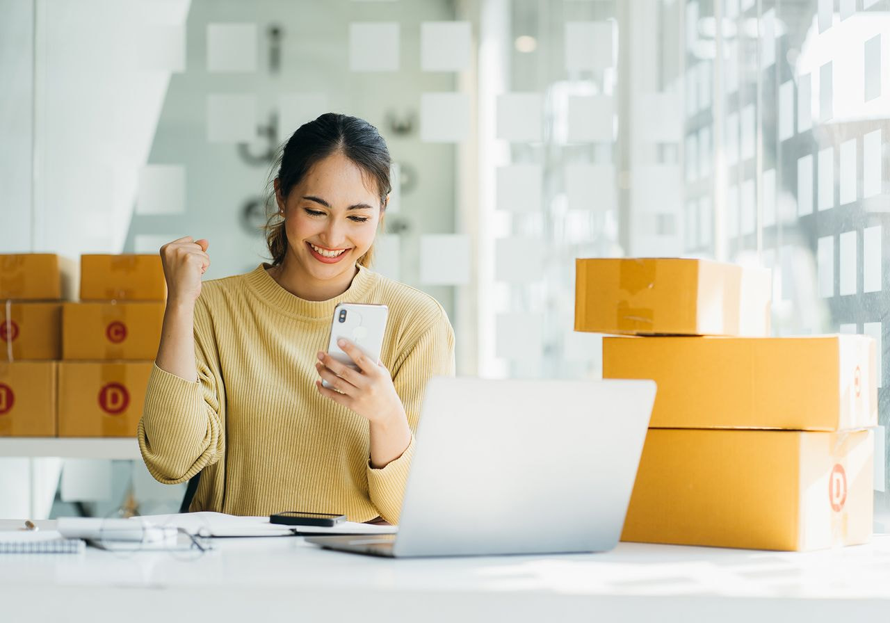 A woman is looking at her phone happily.