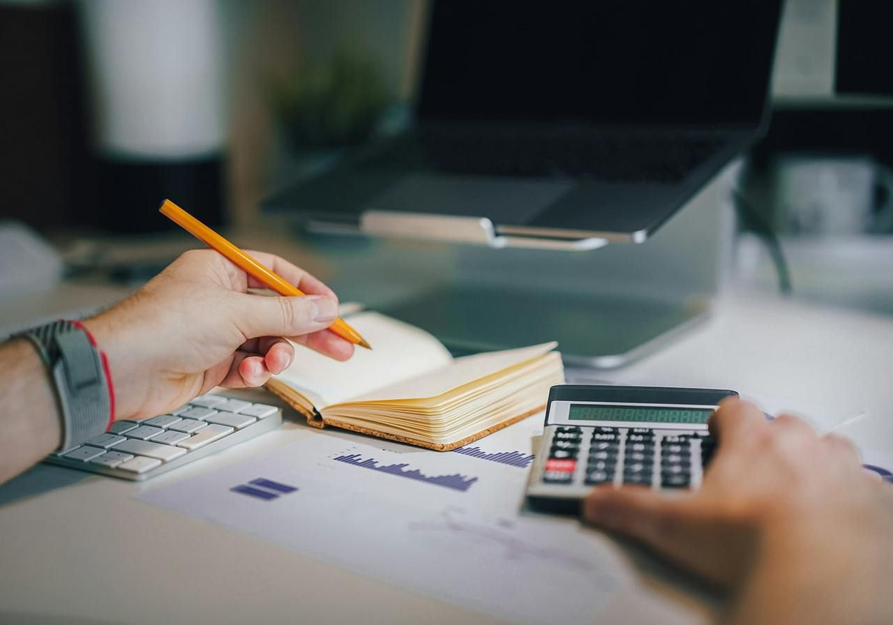 Image illustrating steps to create a business plan, featuring charts, notes, and a laptop on a desk.