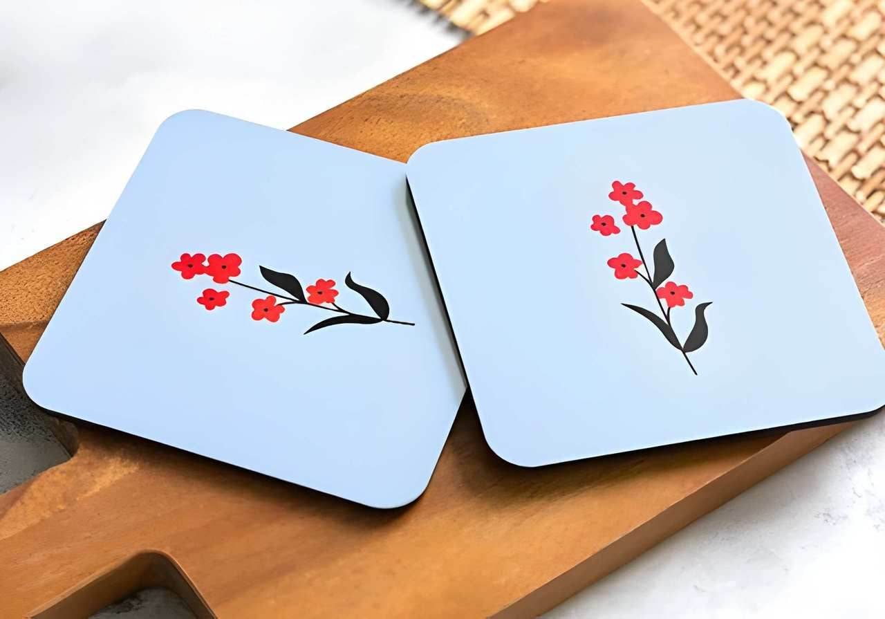 A pair of custom beer coasters with a floral design against a wooden cutting board.