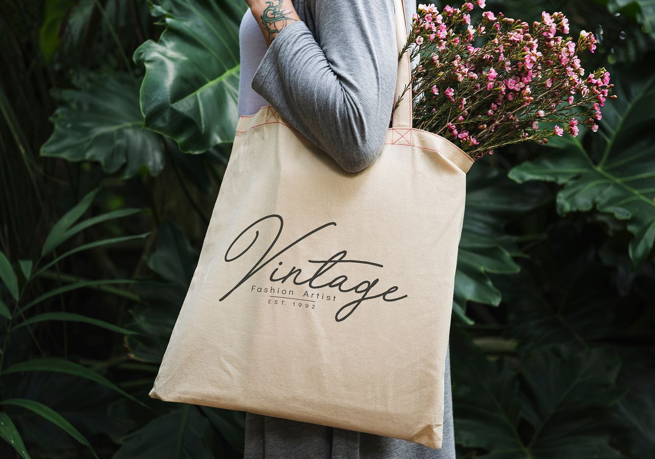 Vintage tote bag mockup displayed on a wooden surface, showcasing its unique design and fabric texture.