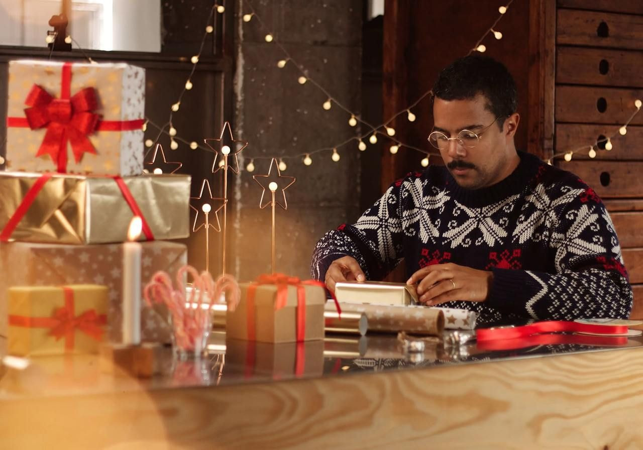 A man in a sweater is focused on working at his computer, typing and engaging with the screen.