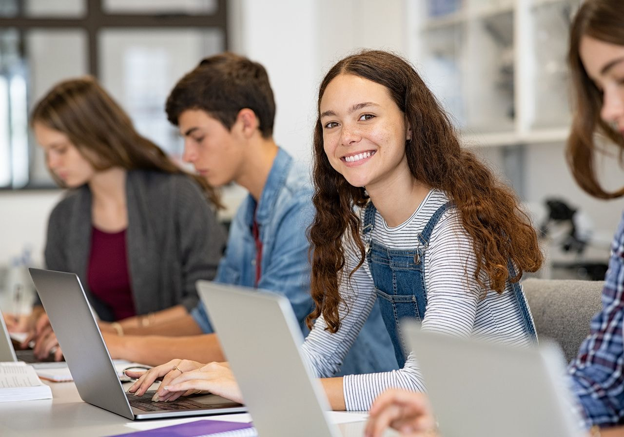 A group of students collaborates at a table, each using a laptop for their work or study session.