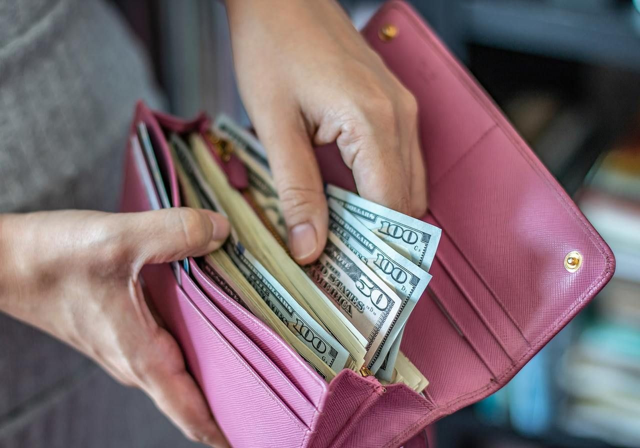 A woman is taking out money from a wallet.