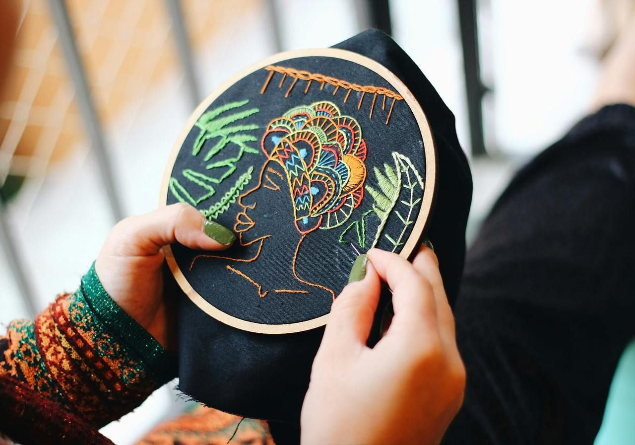 A person holds a black embroidery hoop, showcasing their interest in needlework and crafting.
