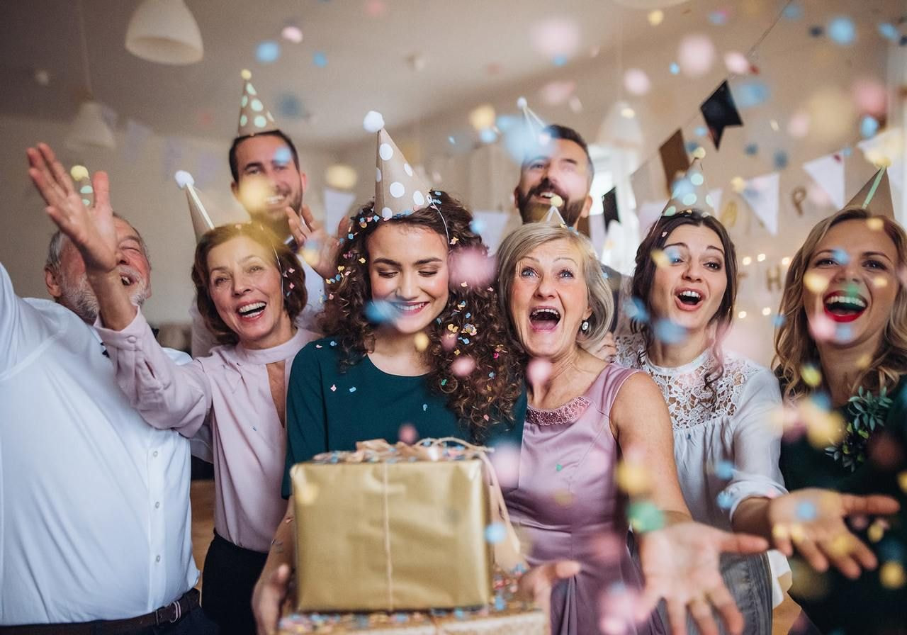 A group of joyful people celebrating a birthday party, smiling and enjoying cake and decorations.