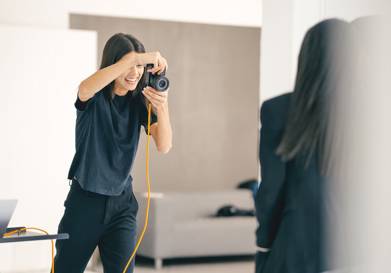 A woman capturing a moment with a camera, focused on her subject in an outdoor setting.