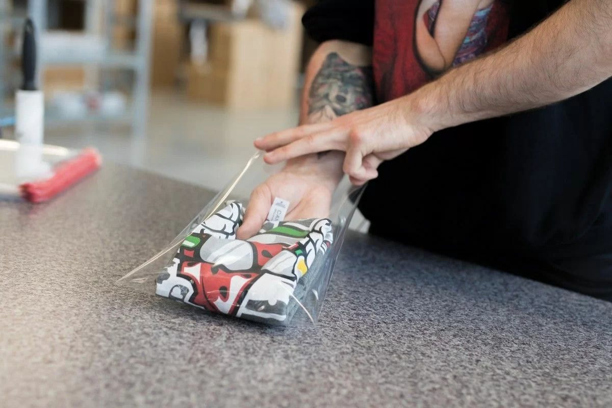 eine Person, die eine Plastiktüte mit einem Hemd darin hält