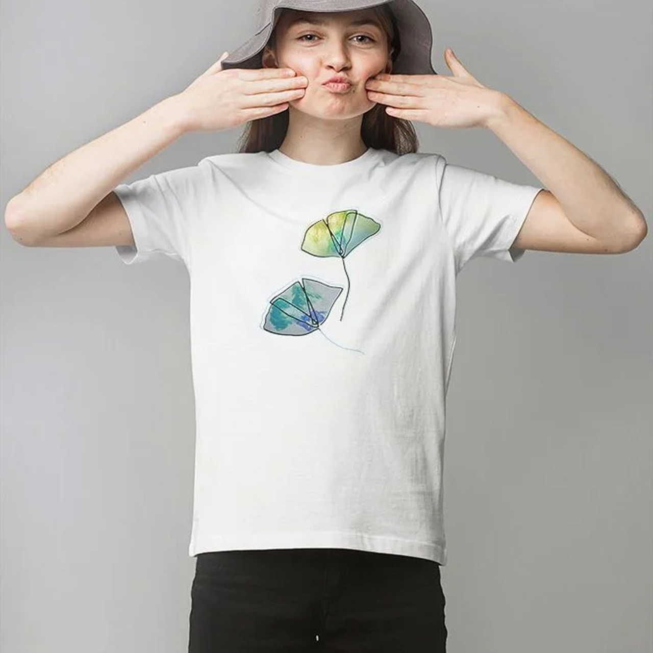 A child wearing a white Organic Cotton Kids T-Shirt | Stanley/Stella STTK184 with a floral print.