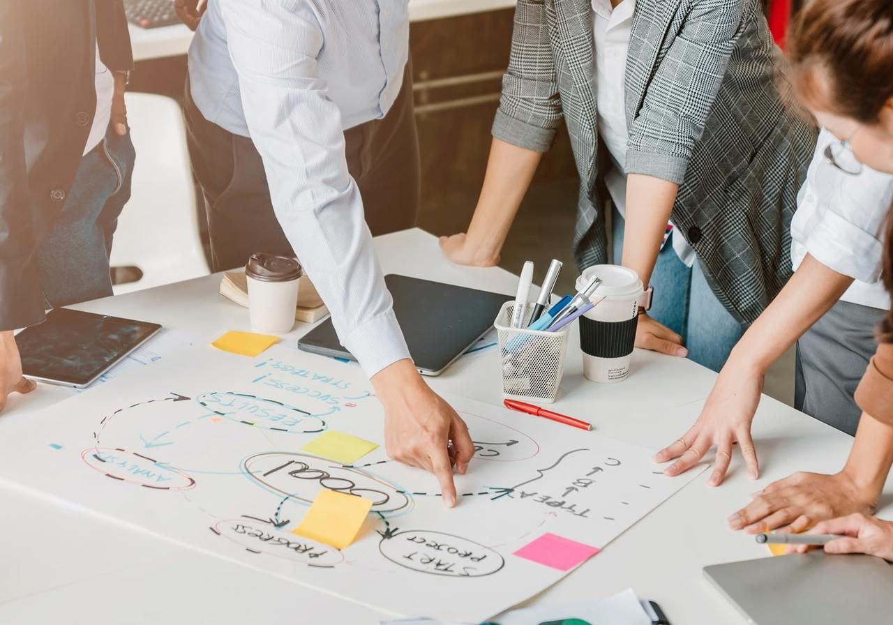 Business professionals collaborating on a whiteboard, discussing ideas and strategies in a modern office setting.