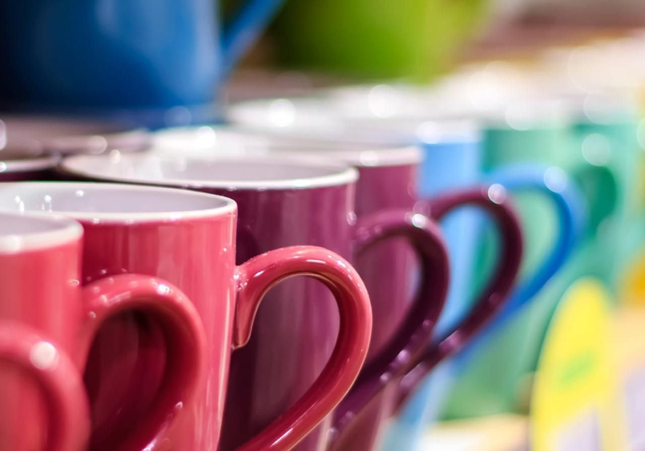  variety of colorful coffee mugs arranged on display shelves in a store, showcasing different designs and patterns.