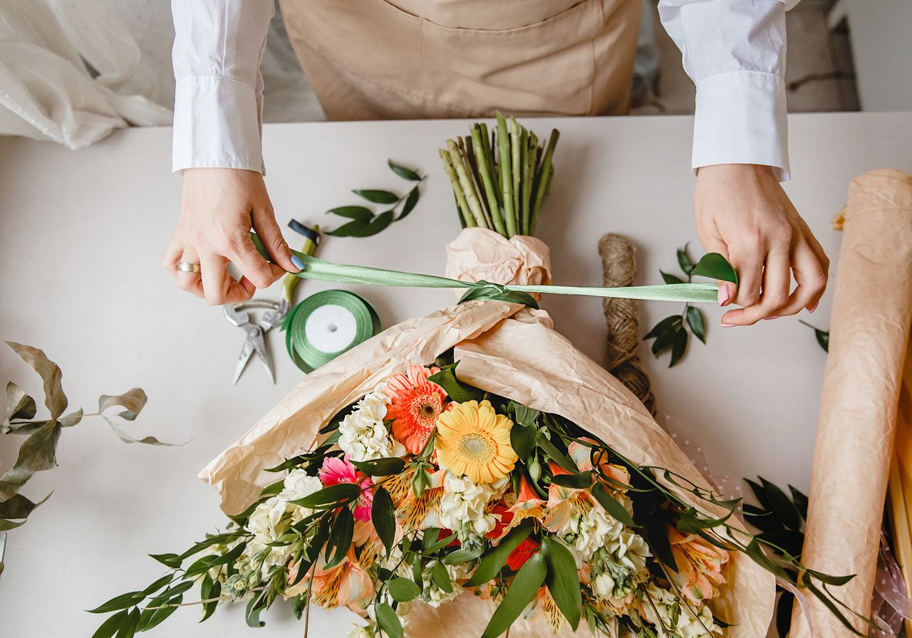 A woman carefully ties a vibrant bouquet of flowers.