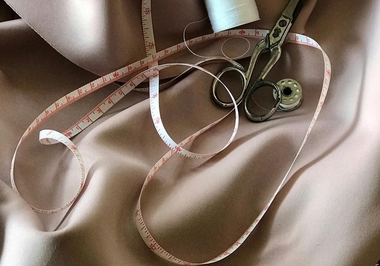A pair of scissors and a measuring tape resting on a piece of cloth, suggesting a sewing or crafting activity.