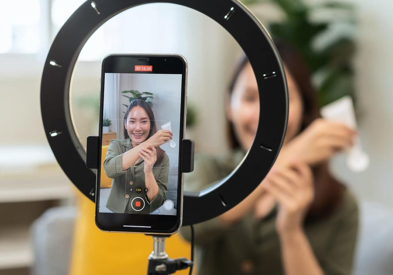 A woman is using a mobile phone and recording herself promoting products.