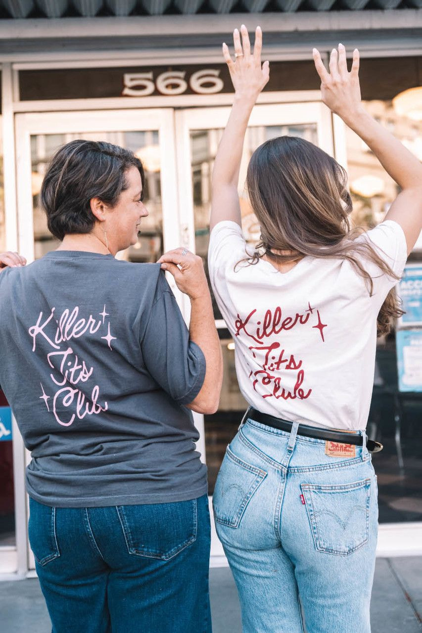 two women holding their shirts