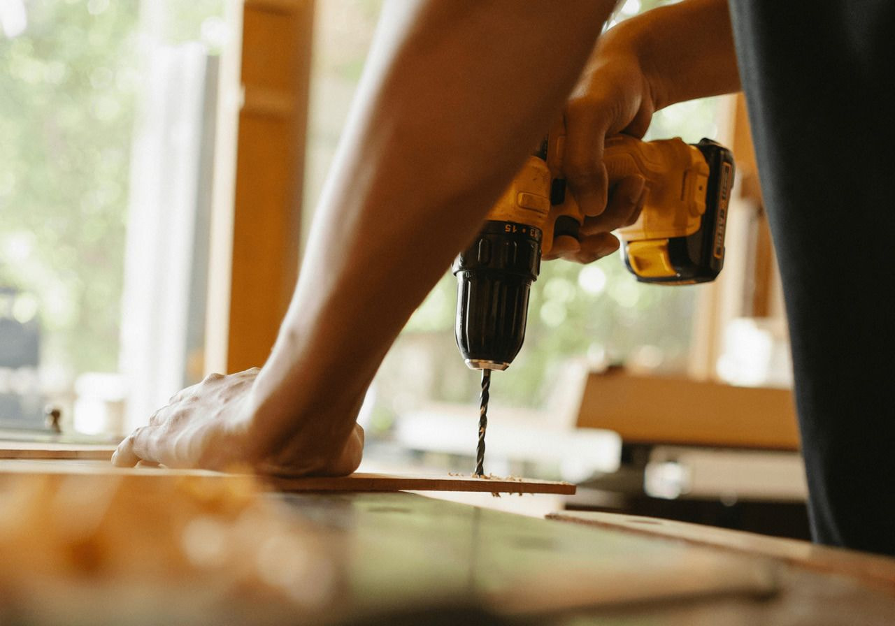 A person operating a drill to create a hole in a piece of wood.