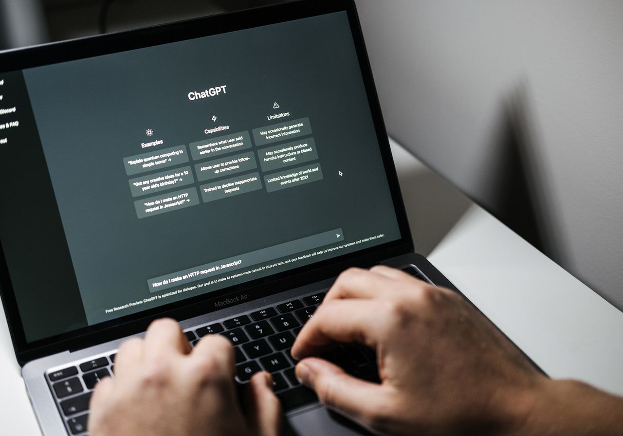Hands typing on a laptop displaying the ChatGPT interface.