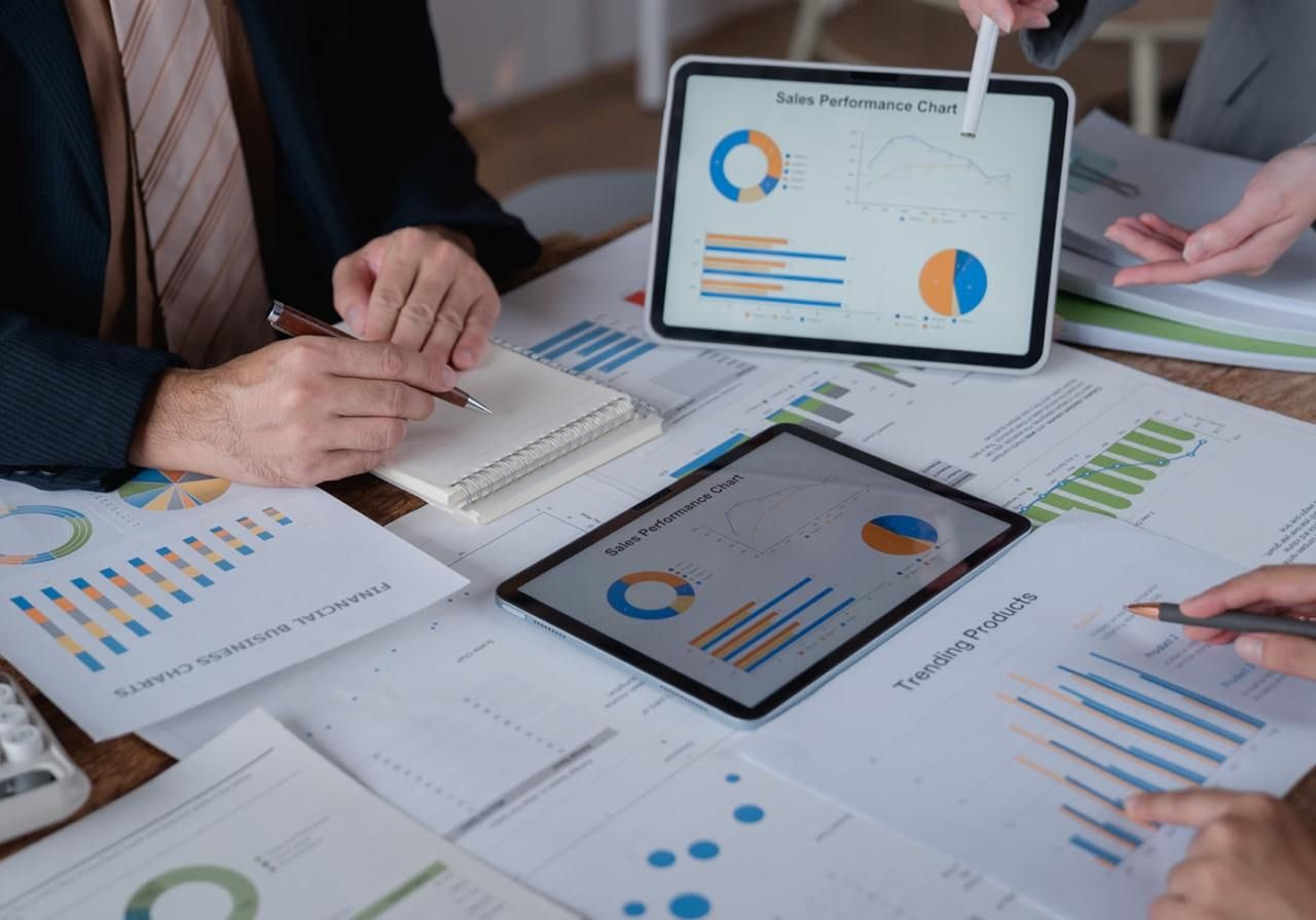 Business professionals collaborating at a table covered with graphs, charts, and documents.