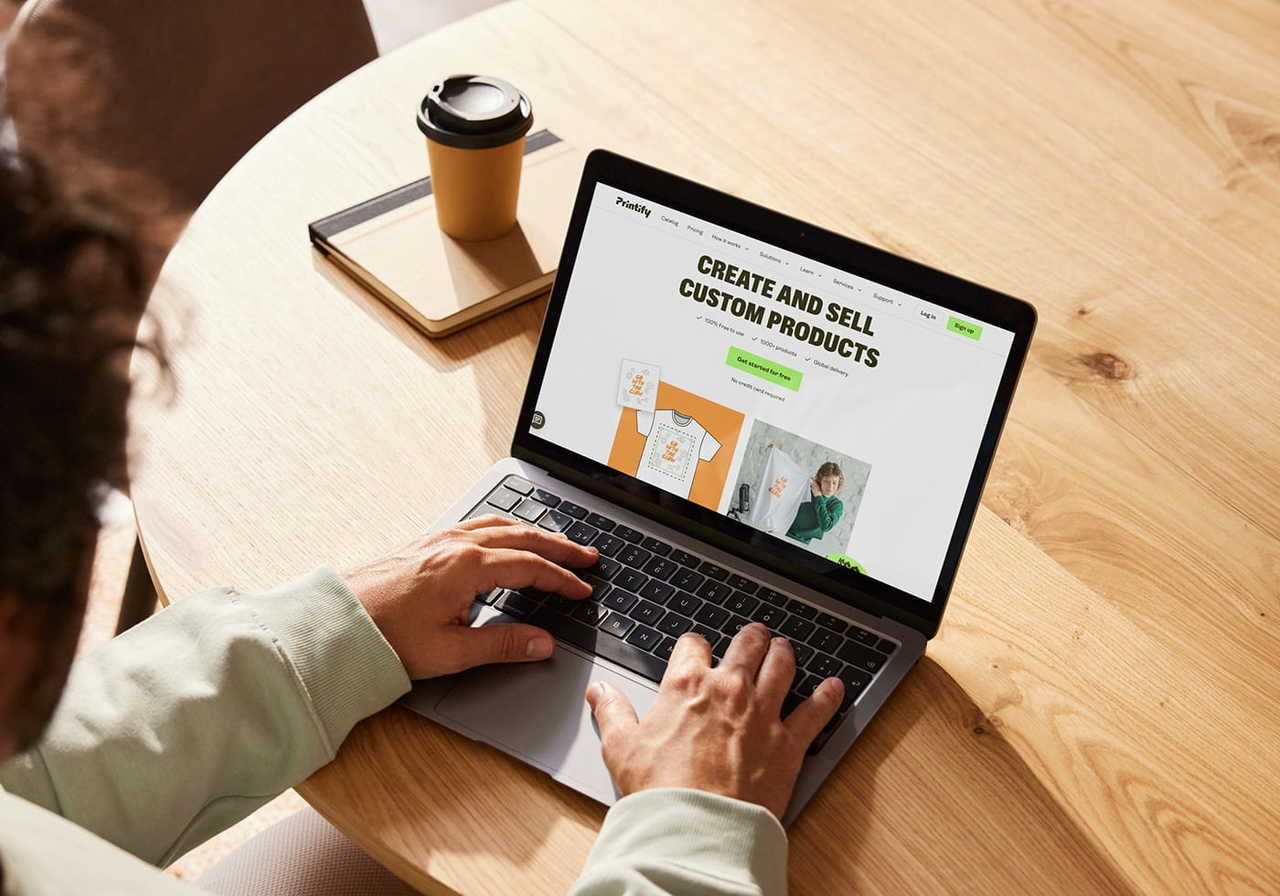 A person using a laptop with Printify’s homepage on the screen.