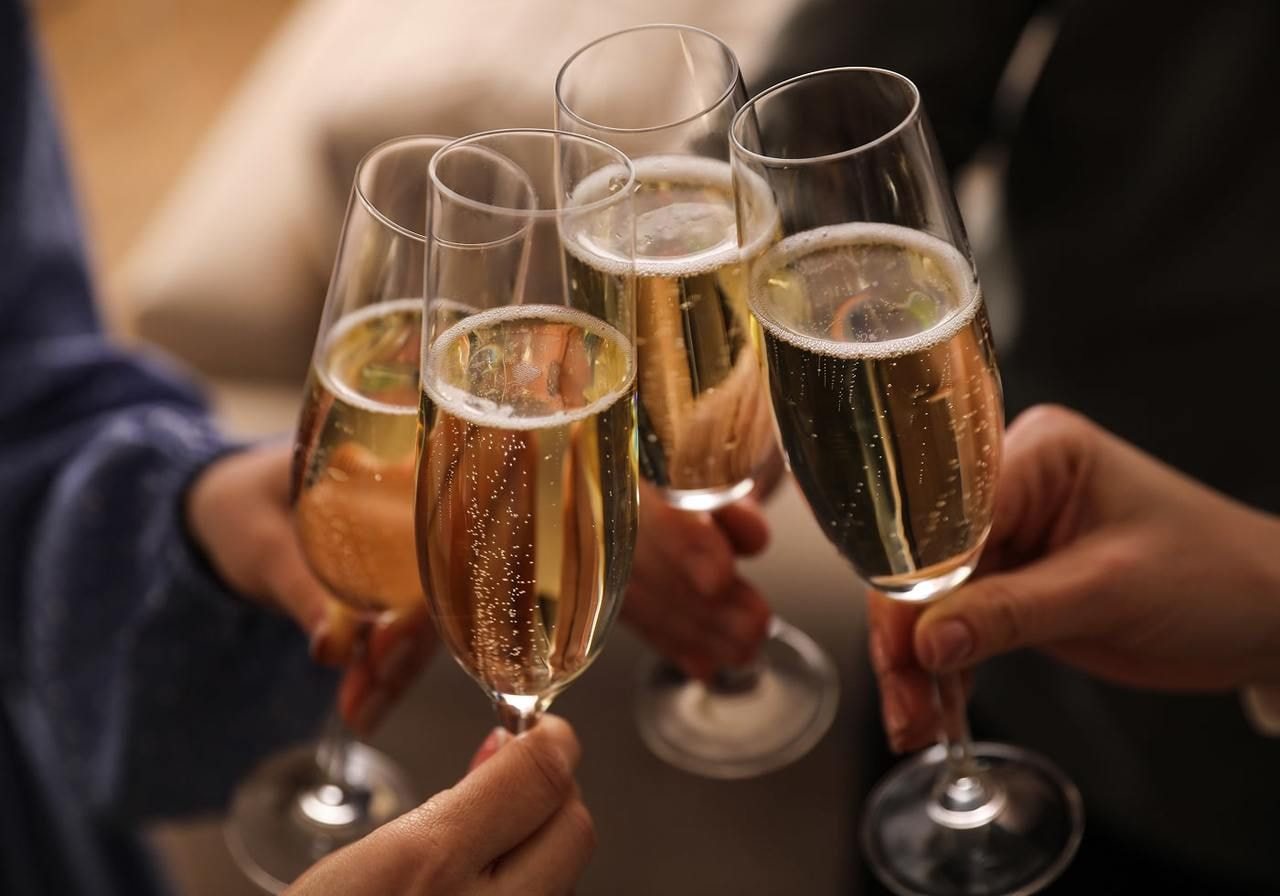 Four people cheerfully holding glasses of champagne, celebrating together in a festive atmosphere.