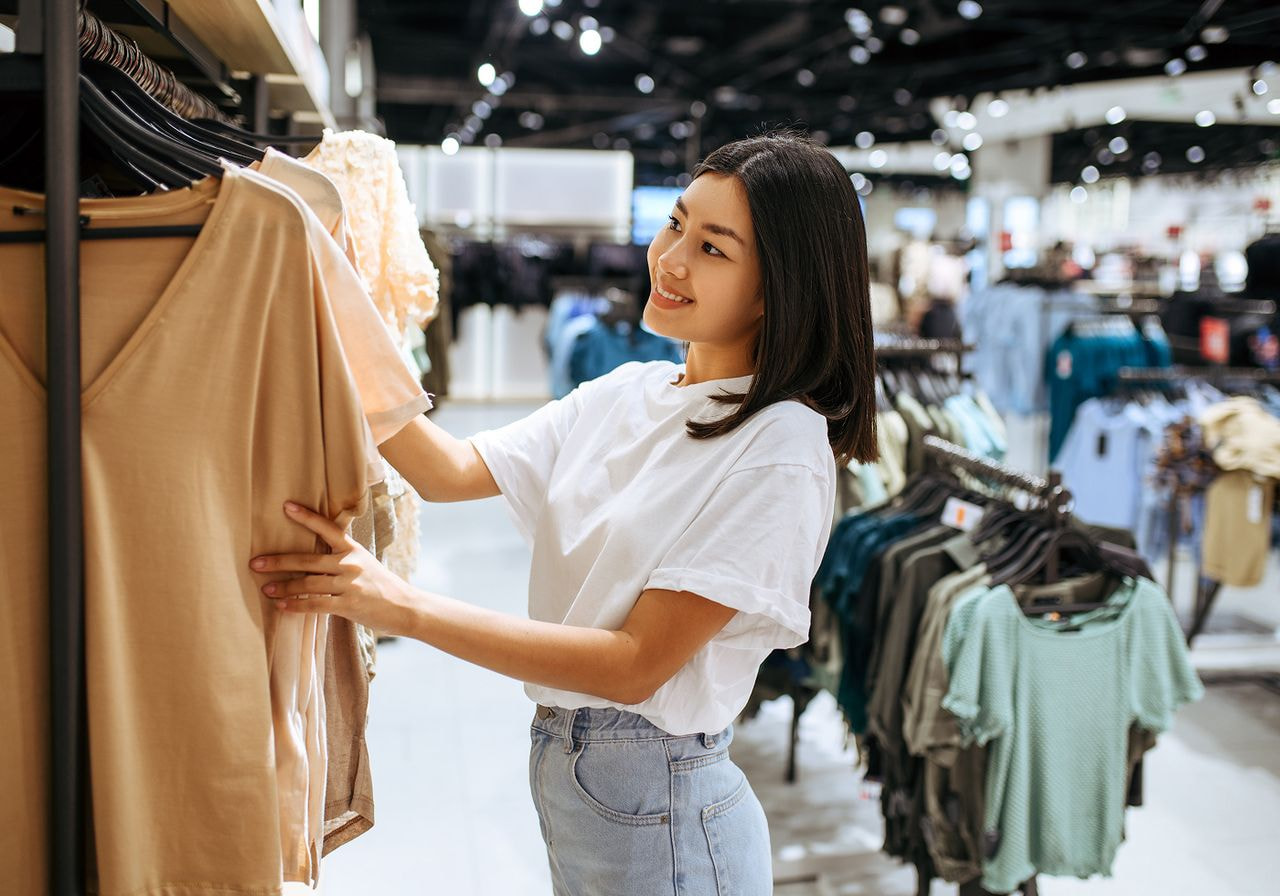 A woman examines clothing on display in a retail store, considering her options for purchase.