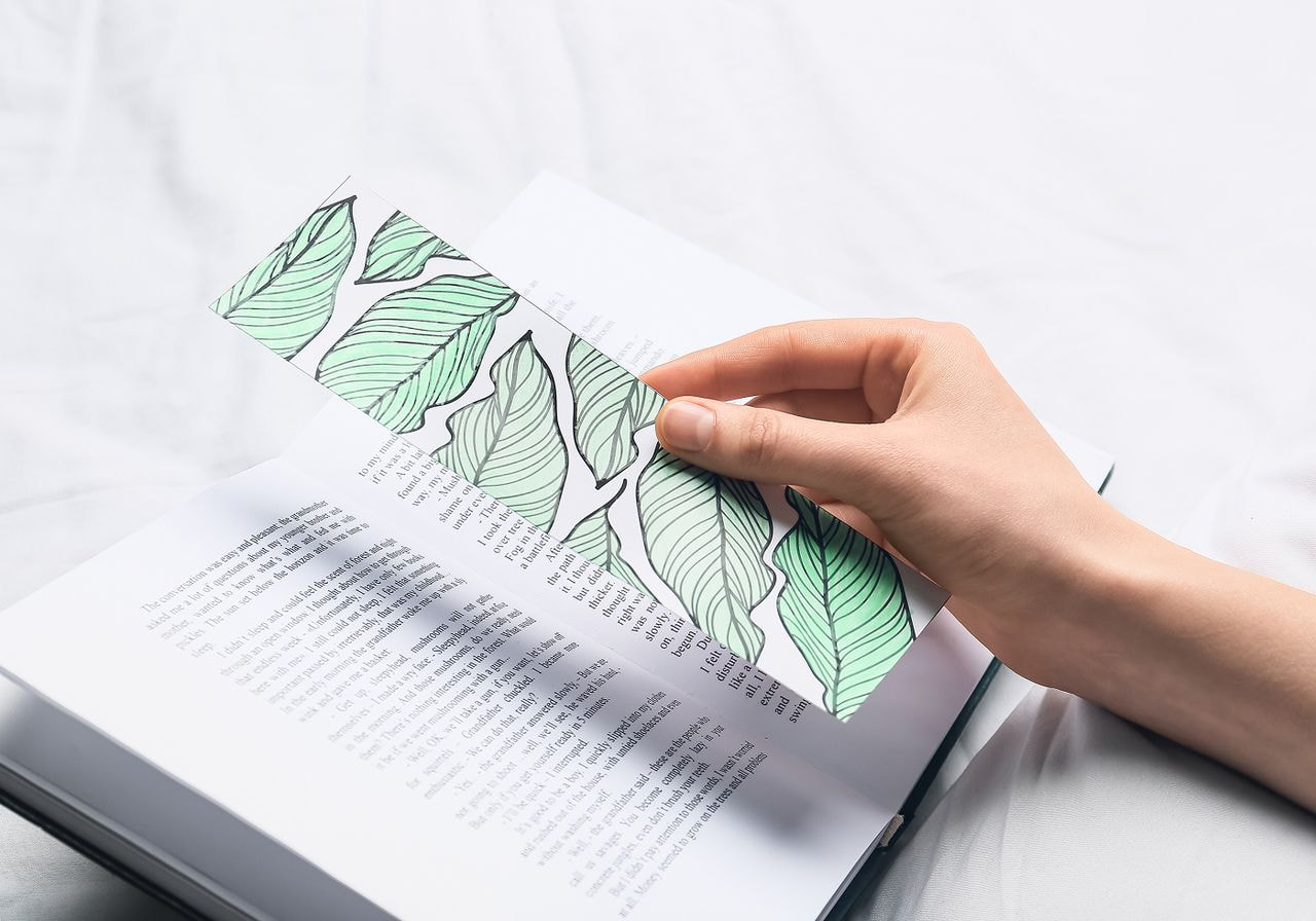 A person reading a book adorned with green leaves, immersed in the content.