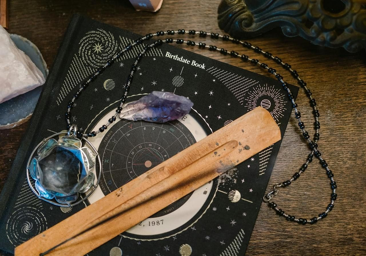 A book, a wooden stick, and a crystal are arranged on a table, showcasing a simple yet intriguing display of objects.