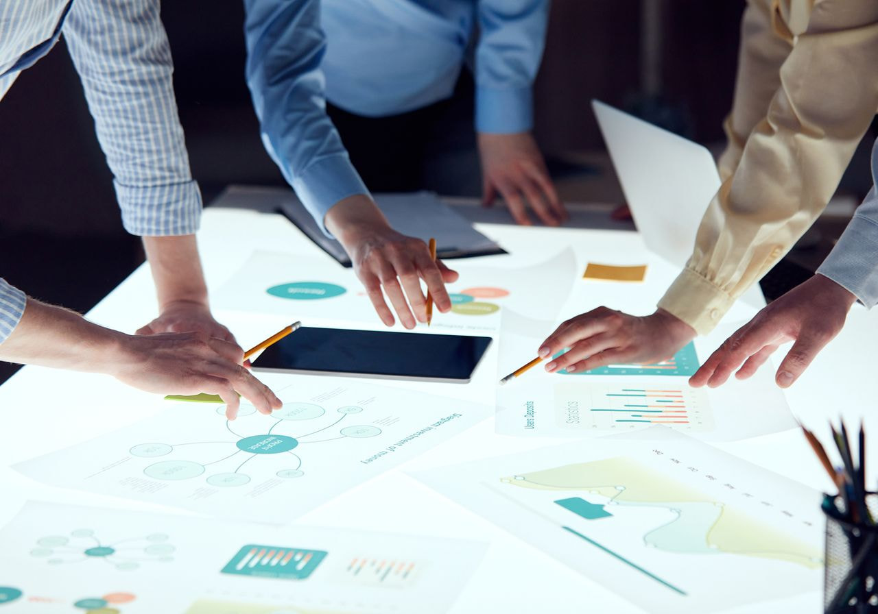 Business professionals collaborating at a table covered with graphs, charts, and documents.