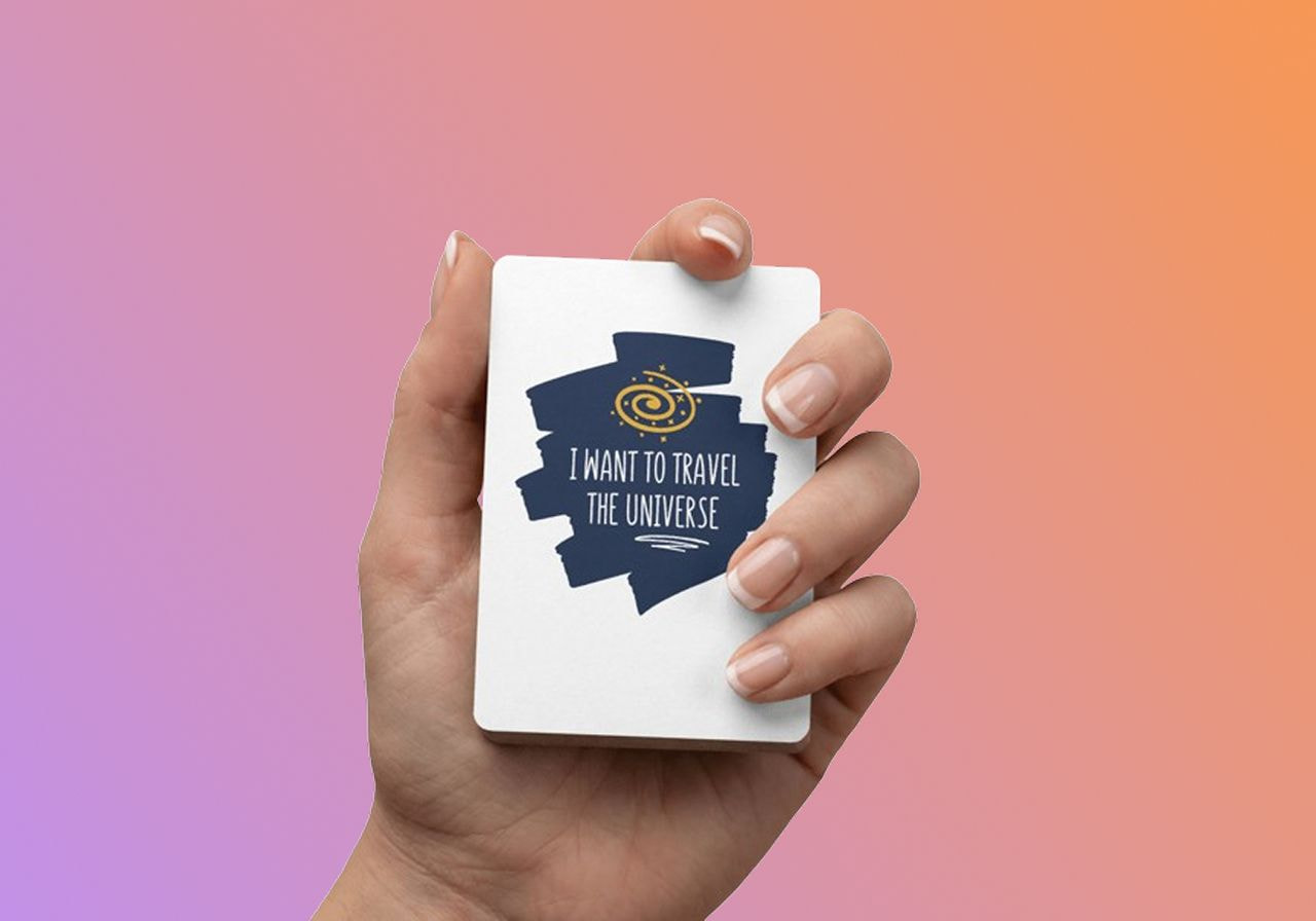 A hand holding a custom deck of playing cards with a “I want to travel the universe” space-themed print.